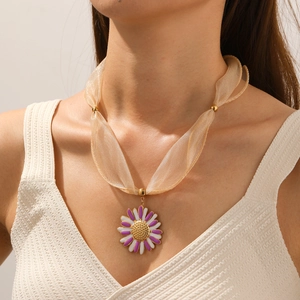 Close-up of a purple and white daisy flower pendant on a champagne organza silk chain