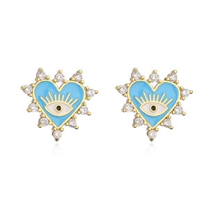 Macro detail of 18K gold earrings with blue enamel evil eye and sparkling crystals