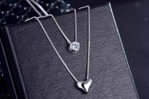 Close-up of double-layer silver heart necklace and zircon pendant on black jewelry box