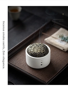 Close-up of ceramic incense burner with metal hollow lid on tea tray with smoke effect