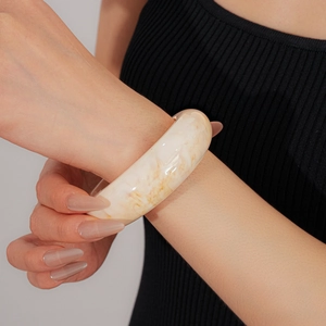 Close-up of wide resin bangle with marble texture on wrist against black sweater