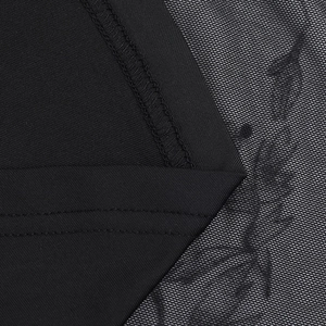 Détail macro de tissu noir dense avec dentelle florale délicate et coutures renforcées