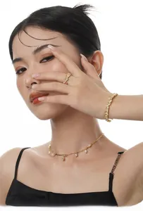 Detail of elegant gold jewelry set with rectangle zircons and dangling pearls on model
