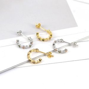 Detail of C-shaped hoop earrings featuring colorful cubic zirconia on gold and silver plating