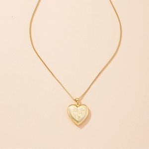 Close-up of golden vintage heart locket necklace that opens on a soft beige background