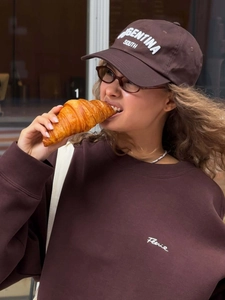 Détail du sweat-shirt marron foncé avec broderie blanche et casquette assortie