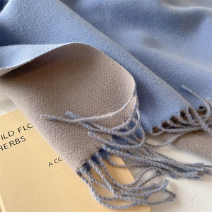 Macro detail of soft blue and beige double-sided scarf with elegant tassel fringe