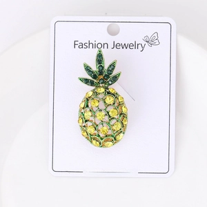 Detailed macro view of pineapple brooch with green and yellow rhinestones on card