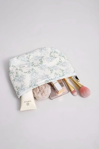 Dettaglio trousse trucco floreale con pennelli e cosmetici all'interno della borsa