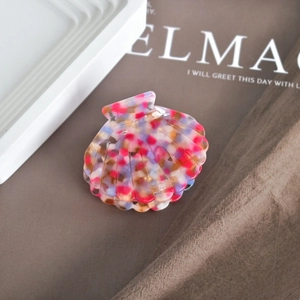 Detailed macro shot of shell-shaped acetate hair claw with colorful mosaic pattern