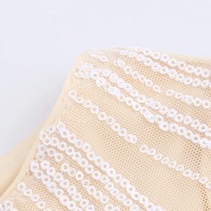 Close-up of white sequins on beige mesh fabric for elegant V-neck sequined dress