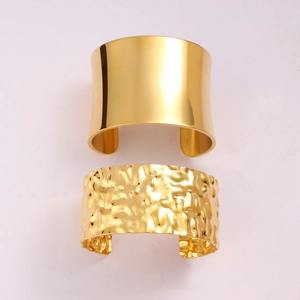 Detail of gold wide bangles showing mirror polished and hammered textures on stainless steel