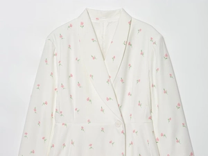 Detail eines weißen Blazers mit rosa Blumenmuster und klassischem Reverskragen für Damen