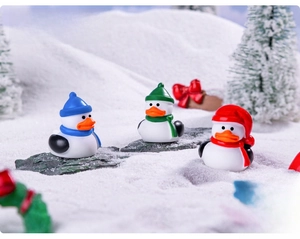 Micro landscape Christmas duck figurines with colorful winter hats on snowy background