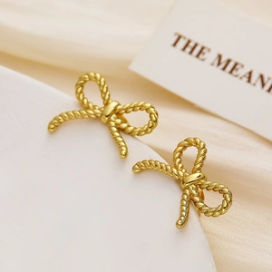 Detail of gold bow earrings featuring an intricate twisted rope texture and metallic finish