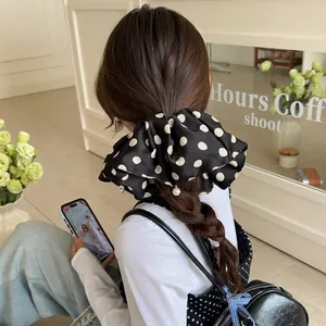 Black oversized polka dot satin scrunchie with elegant pearl charm on a ponytail