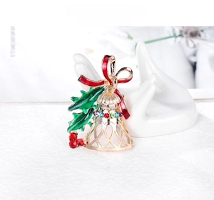 Detail of Christmas bell brooch with red bow and multi-color rhinestones on white display