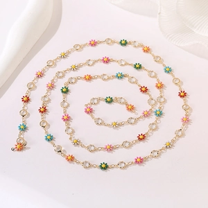 Detail showing colorful enamel daisy flowers and crystal beads on a golden chain necklace
