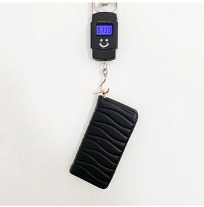 Macro shot showing the 130g weight of a black quilted wave pattern long zipper wallet