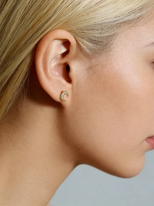 Close-up of a gold crescent moon earring with micro-paved zircons worn by a model