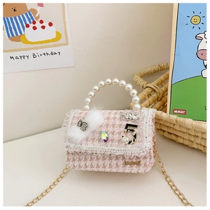 Detail of girls mini pearl handbag with pink houndstooth texture and crown brooch