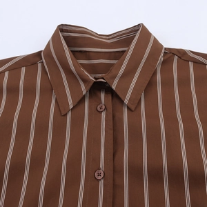 Close-up of brown long sleeve shirt collar with white vertical stripes and button detailing