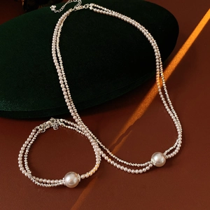 Detailed view of pearl jewelry set with silver charms on green velvet and leather
