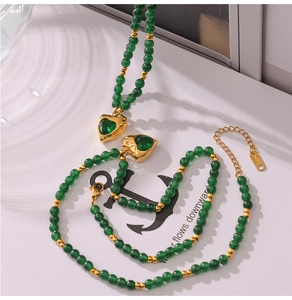 Détail d'un ensemble de bijoux en perles vertes avec pendentif cœur doré et pierre sertie