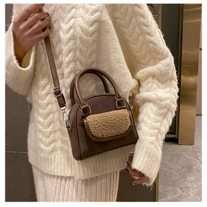 Detail of dark brown faux suede handbag with beige plush trim and adjustable shoulder strap