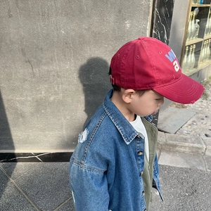 Detail of red kids baseball cap with letter embroidery and blue denim jacket