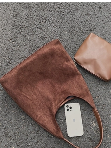 Detail of dark brown suede tote bag with matching leather coin purse on pavement