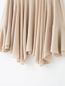Detail shot of the layered irregular chiffon hem in a soft light beige color