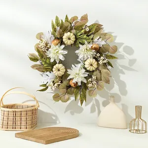 Autumn harvest wreath with white pumpkins and dahlias hanging on a white wall
