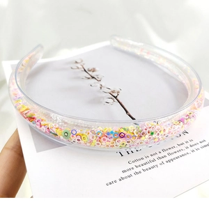 Close-up of transparent hairband filled with colorful sequins and fruit slices on a card