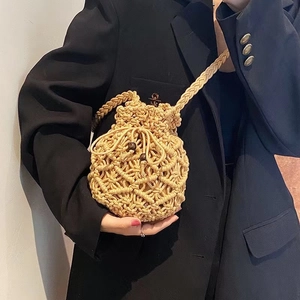 Handmade beige macrame bucket bag with wooden beads shown by model in black blazer