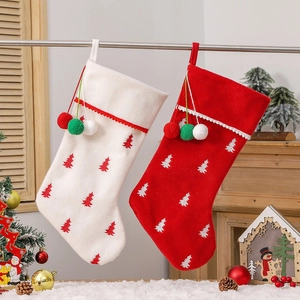 Red and white plush Christmas stockings with tree embroidery and pompoms hanging decor