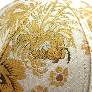 Macro shot of gold floral embroidery on high-quality white jacquard fabric baseball cap