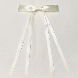 Macro detail of silky ivory polyester ribbon bow hair clip with elegant long streamers