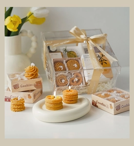 Vista detallada de velas aromáticas con forma de galleta en una caja de regalo transparente