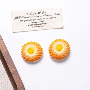 Close-up of resin daisy accessories with orange gradient finish for DIY crafts