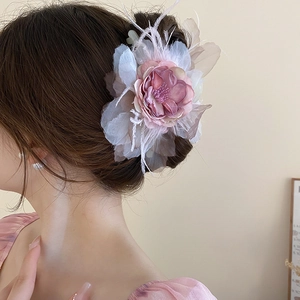 Detail of pink and purple fabric rose hair claw clip with white feathers on long hair