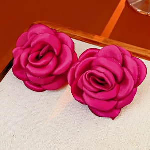 Macro detail of magenta rose flower accessories made of silk satin on beige woven fabric
