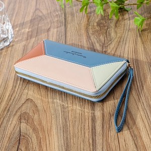 Detailed view of women's long patchwork leather wallet with wrist strap and gold zipper