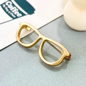 Minimalist gold hollow glasses brooch with polished metal finish on a neutral backdrop