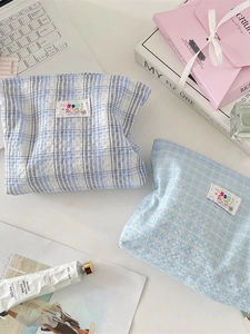 Blue plaid makeup pouch set featuring two soft fabric cosmetic storage bags on a desk