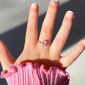 Detail of child gold ring featuring an oval pink gemstone and textured band
