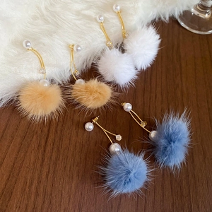 Detail showing plush fur pompom and pearl earrings in white, beige, and blue colors