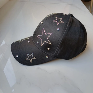Detailed view of black cotton baseball cap with sparkling rainbow rhinestone star patterns