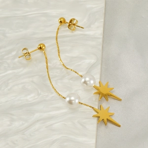Detailed close-up of gold star earrings with pearl charms and long fringe chains