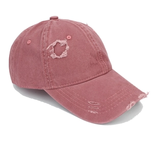 Close-up of distressed pink cotton baseball cap featuring vintage ripped and frayed details